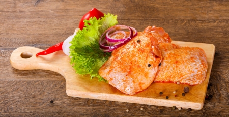 raw marinated chicken pieces on a cutting board